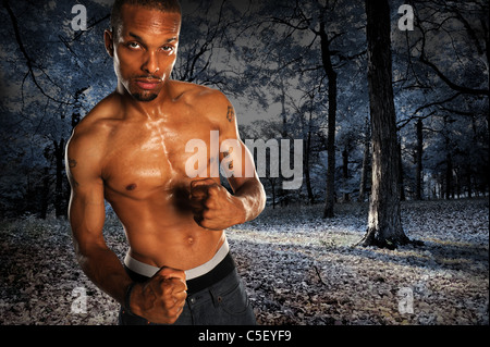 African American man avec ses poings fermés sur paysage sombre Banque D'Images