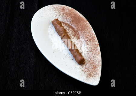 Une praline au chocolat sur une plaque blanche avec du cacao en poudre Banque D'Images