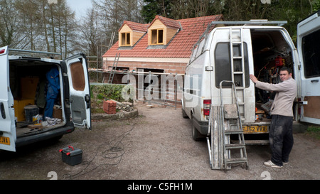 Un jeune homme de travail sur une nouvelle maison sur un chantier de l'extraction tools de l'arrière de son van Gloucestershire England UK KATHY DEWITT Banque D'Images