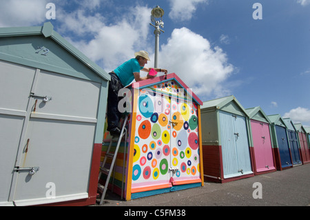 Man painting une cabane de plage dans les Couleurs réglementaires Banque D'Images