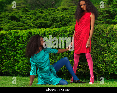 Licence disponible à MaximImages.com - deux belles jeunes femmes portant des couleurs vives habillées dans un parc vert Banque D'Images