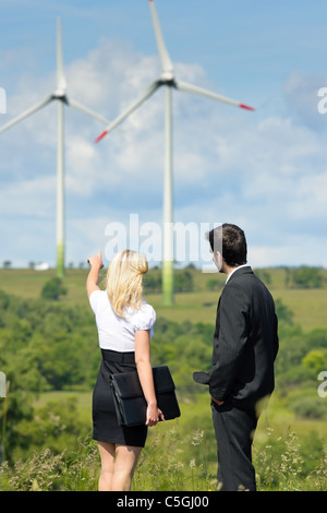 D'affaires de l'énergie verte - Young businesswoman pointing at windmill in field Banque D'Images