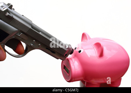 Un pistolet de couleur argent est fait vers une pink piggy bank. Banque D'Images