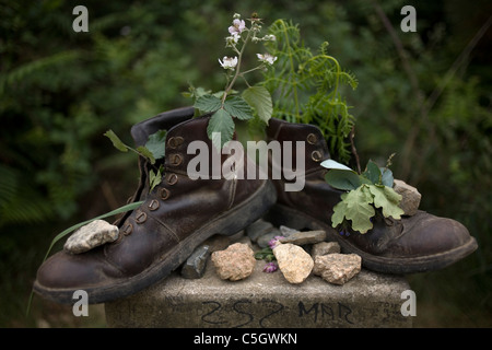 Vieilles bottes remplies de fleurs et plantes placé sur une borne dans le chemin de Saint-Jacques de Compostelle, Santiago de Compostela, Banque D'Images