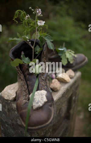 Vieilles bottes remplies de fleurs et plantes placé sur une borne dans le chemin de Saint-Jacques de Compostelle, Santiago de Compostela, Banque D'Images