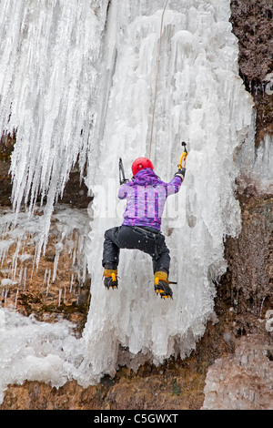 Homme avec piolets et crampons d'escalade sur cascade de glace Banque D'Images