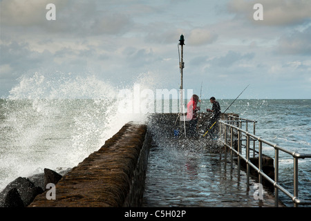 Grosse Vague s'écrase sur la défense de la mer et les pêcheurs en mer deux projections à Lynton sur la côte nord du Devon, England, UK Banque D'Images