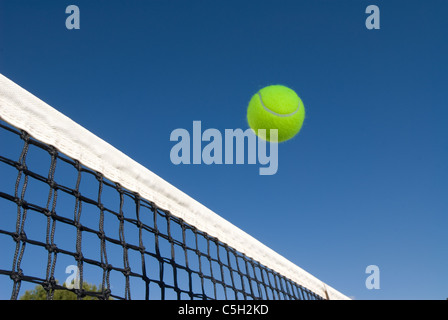 Une image illustrant le concept de tennis, y compris une boule de glisser sur le net dans un cadre extérieur bleu Banque D'Images