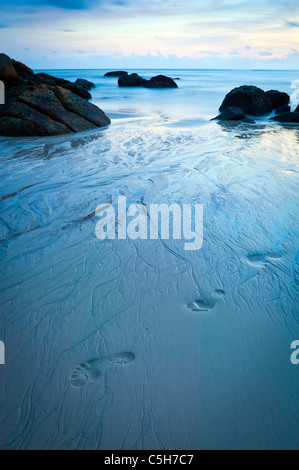 Time-lapse de plage au crépuscule avec des empreintes dans le sable Banque D'Images