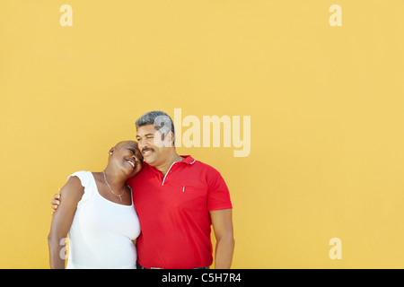 Amérique latine mature couple hugging and smiling avec mur jaune en arrière-plan. Jusqu'à la taille, copy space Banque D'Images