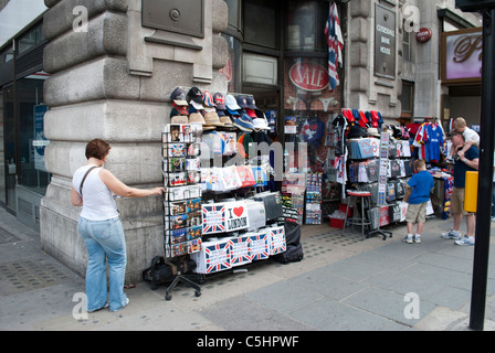 Femme à la recherche de cartes postales à l'extérieur de magasin de souvenirs touristiques près de Piccadilly Circus Banque D'Images
