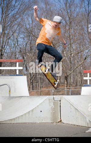 Portrait d'un jeune skateur professionnel effectuant un saut au skate park. Banque D'Images