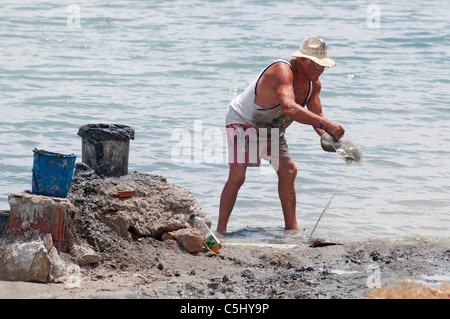 L'homme Local creuse à boue thérapeutique sur le littoral à Lo Pagan, Région de Murcie, Espagne, Europe du sud-est Banque D'Images