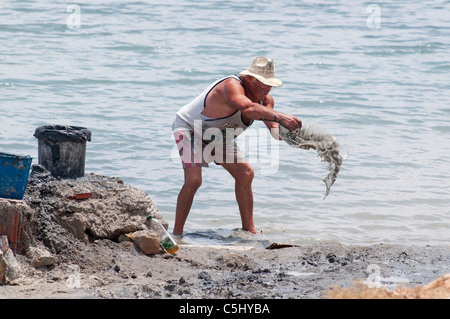 L'homme Local creuse à boue thérapeutique sur le littoral à Lo Pagan, Région de Murcie, Espagne, Europe du sud-est Banque D'Images