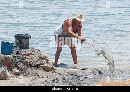 L'homme Local creuse à boue thérapeutique sur le littoral à Lo Pagan, Région de Murcie, Espagne, Europe du sud-est Banque D'Images