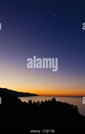 Croissant de lune et l'aube lumière sur la côte de Big Sur, en Californie Banque D'Images