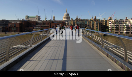 Vue éloignée sur la Cathédrale St Paul sous un ciel d'été bleu, vu depuis le Millenium Bridge avec les piétons qui traversent, Londres Banque D'Images