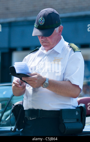 Un gardien de la circulation l'écriture d'un billet pour une voiture en stationnement illégal. Stratford sur Avon. UK Banque D'Images