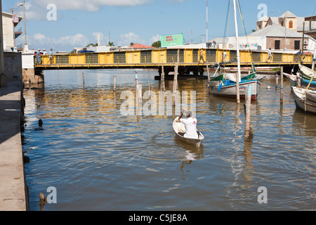 Aviron Canoë bateau type homme sur Haulover Creek, près de pont tournant, à Belize City, Belize Banque D'Images