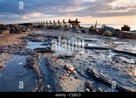 La première lumière illuminait la mer à Happisburgh abandonnés de défense sur la côte de Norfolk Banque D'Images