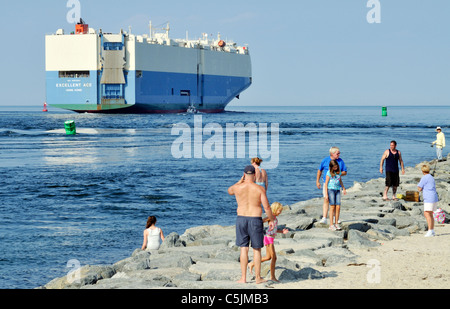 Cargo transporteur de voiture Excellent Ace quitter le Cape Cod Canal dans la baie dirigée pour mer ouverte avec les gens on jetty en maillots de regarder. USA Banque D'Images