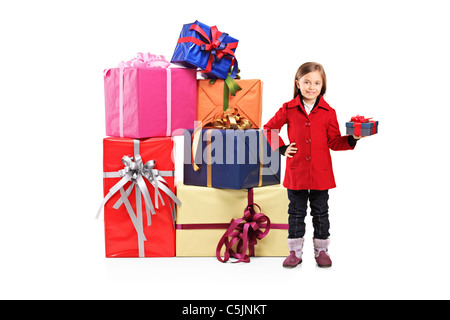 Portrait d'un enfant tenant un cadeau et posant à côté d'une pile de cadeaux Banque D'Images