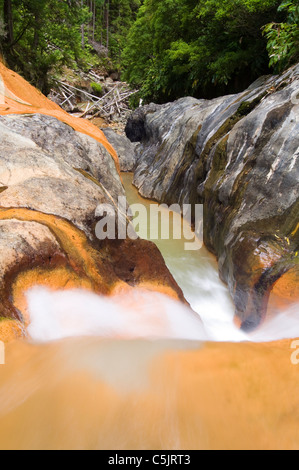Au sommet de la cascade à Lombadas, ville de Ribeira Grande, île de St Michaels, Açores, Portugal. Ruisseau riche en fer avec eau teintée orange qui coule. Banque D'Images