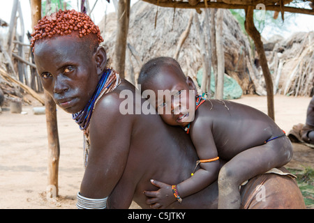 Portrait d'un tribeswoman Karo et son bébé moudre le grain au village de Kolcho dans la basse vallée de l'Omo, dans le sud de l'Éthiopie. Banque D'Images