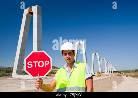 Un ouvrier de la construction où l'arrêt du trafic ferroviaire traverse une route à grande vitesse en cours de construction Banque D'Images