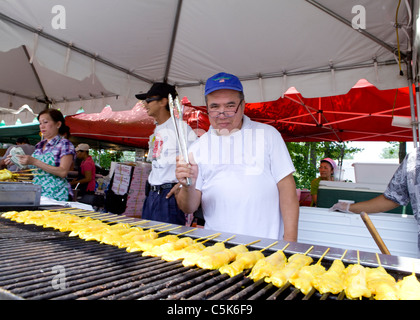 L'homme asiatique brochettes de poulet cuisson sur grill - USA Banque D'Images