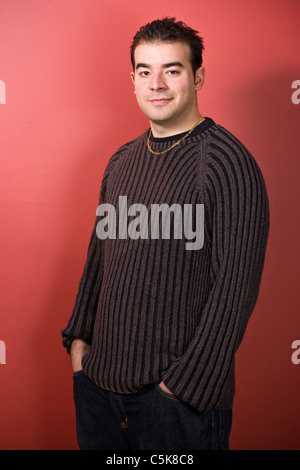 Portrait d'un jeune homme dans la vingtaine sur un fond rouge. Banque D'Images