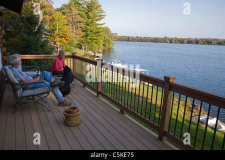 Couple avec chien profiter de vue sur le lac au bord du lac de la maison. Banque D'Images