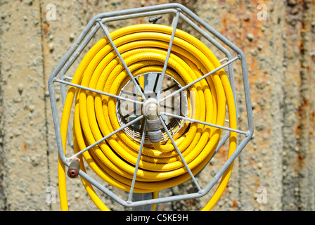 Un tuyau de jardin jaune sur une bobine à un port de plaisance. Banque D'Images