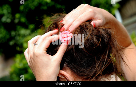Jeune femme ajuste fleur rose dans les cheveux Banque D'Images