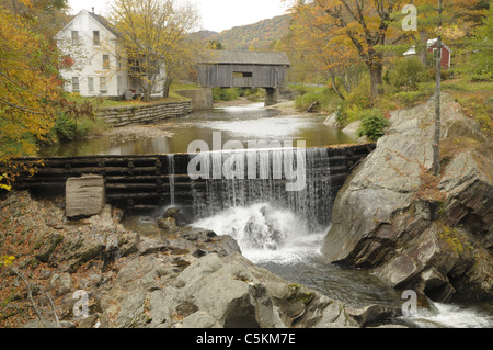 Sur un pont couvert à l'arrière-plan, l'eau coule sur un barrage à l'automne dans la région de Warren, dans le Vermont. Banque D'Images