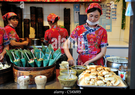 Mesdames travaillant dans un magasin de vente d'aliments de collation à saveur locale du Sichuan. Chengdu, Sichuan, Chine. Banque D'Images