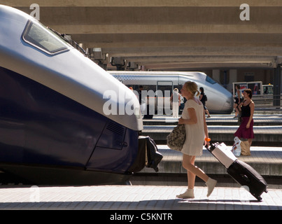 Les passagers à la gare centrale avec deux trains en attente à plates-formes, une femme roulant son sac en premier plan, Oslo, Banque D'Images