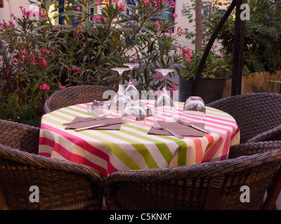Un restaurant en plein air avec table bar d'nappe, couverts et verres, et 4 chaises de paille, Arles, France Banque D'Images