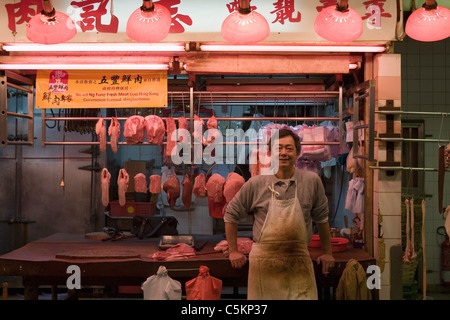 Boucher à son échoppe dans un marché couvert à Hong Kong, Chine Banque D'Images