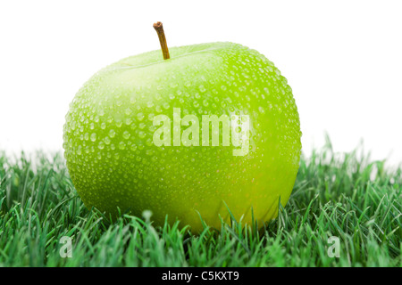 Pomme verte sur l'herbe humide Banque D'Images