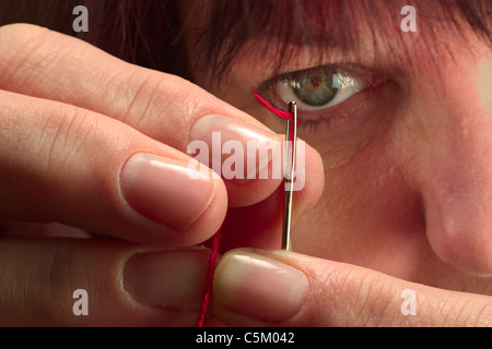 Femme se concentrant sur enfiler une aiguille Banque D'Images