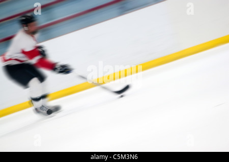 Résumé flou de mouvement d'un joueur de hockey de la manipulation la rondelle comme il accélère vers le bas la glace. Banque D'Images