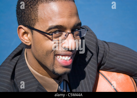 African American man dans un costume d'affaires posant avec un terrain de basket-ball. Il pourrait être un joueur entraîneur recruteur ou formateur. Banque D'Images