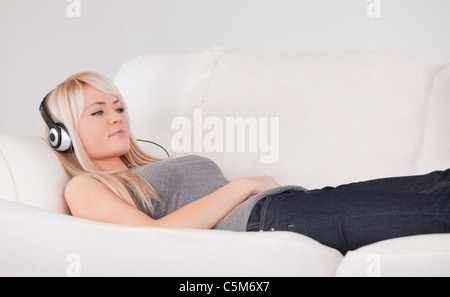 Heureux jeune femme blonde avec un casque couché dans un canapé Banque D'Images