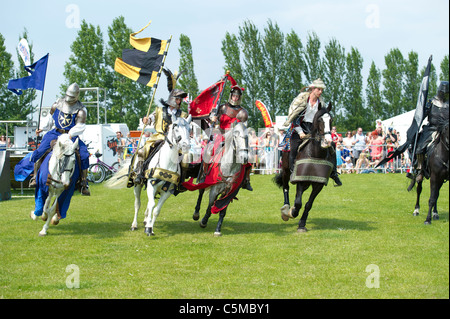 Un groupe de cavaliers habillés comme des chevaliers à cheval autour de l'arène à un spectacle sur un jour d'été dans l'Essex. Banque D'Images