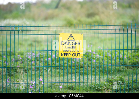 Une section de la clôture de sécurité en acier vert affichant un "danger, activités d'enfouissement, Garder hors'. Banque D'Images