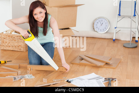 Jolie femme rousse à l'aide d'une scie Banque D'Images