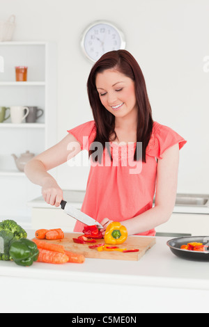 Jeune femme aux cheveux rouge attrayante des carottes de coupe dans la cuisine Banque D'Images