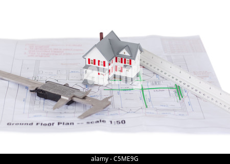 Toy house model et d'une règle et d'un plan sur un fond blanc. Banque D'Images