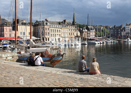 Des couples assis sur le mur du port à Honfleur, Normandie, France Banque D'Images